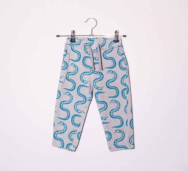 organic cotton sweatpants with teal snake print hanging on a hanger