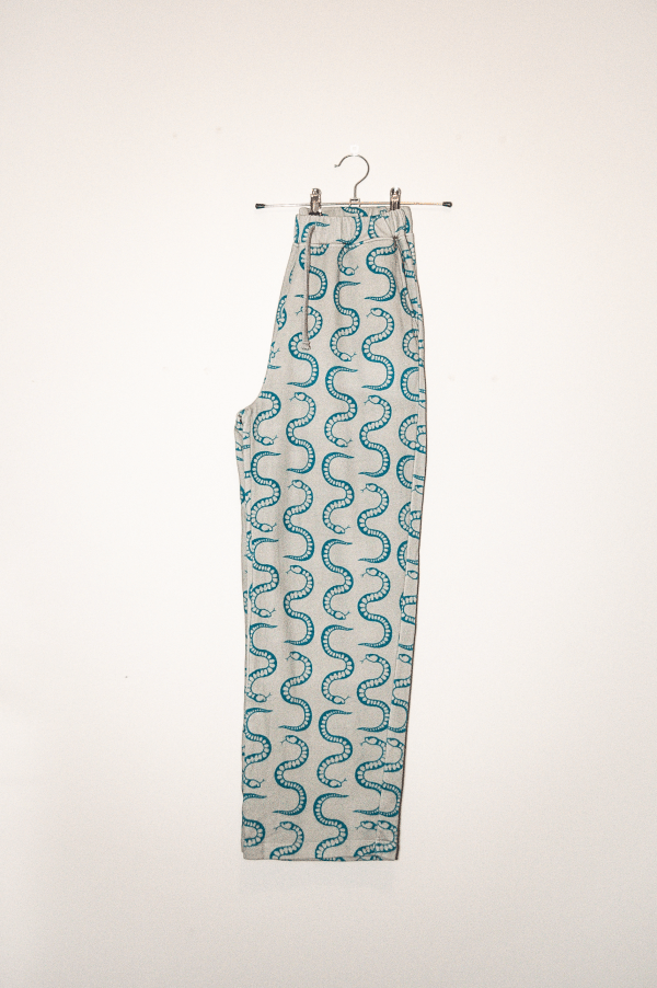organic cotton sweatpants with teal snake print hanging on a hanger