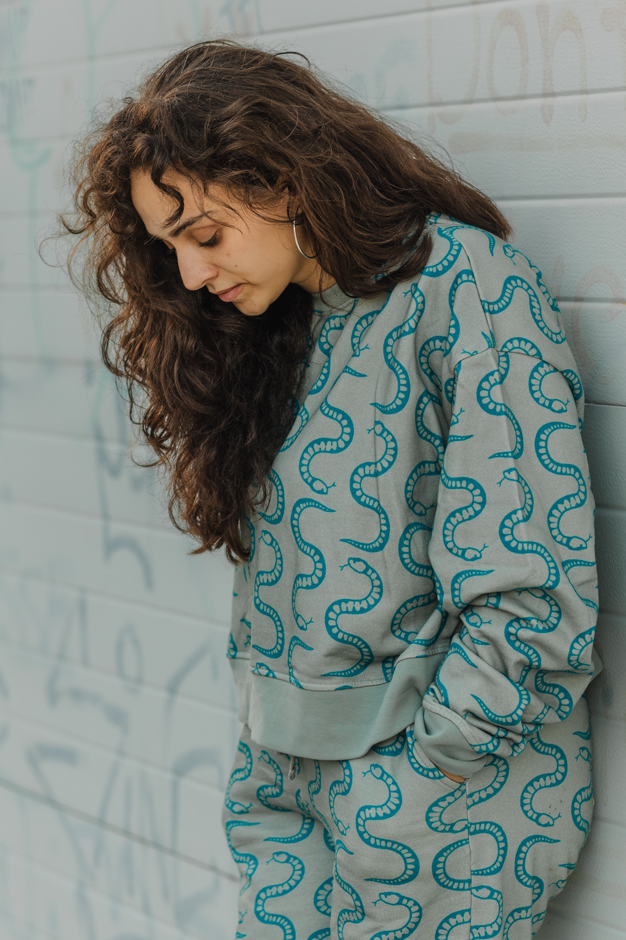woman wearing matching sweatshirt and sweatpants with teal snake print from coisa boa